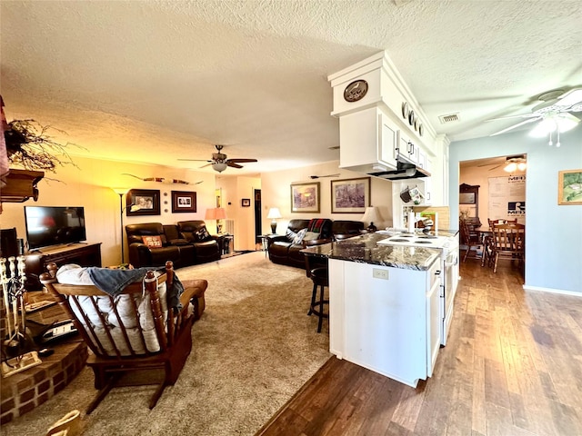 kitchen with white range with electric cooktop, white cabinetry, dark stone countertops, a kitchen bar, and dark hardwood / wood-style flooring