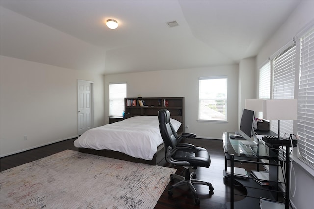 bedroom with multiple windows, dark wood-type flooring, and lofted ceiling