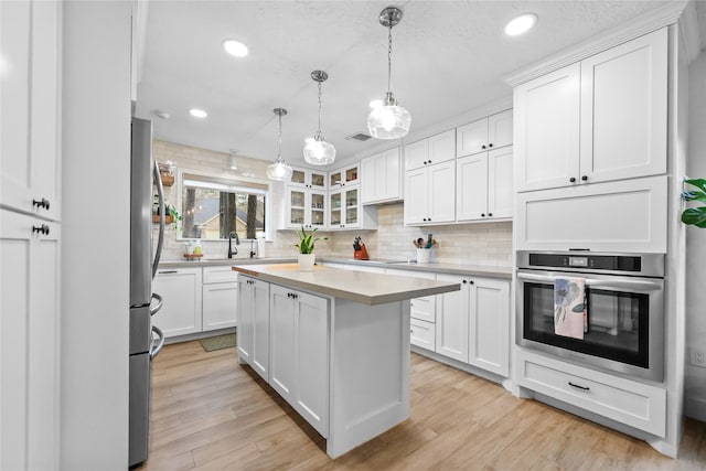 kitchen featuring stainless steel appliances, light wood finished floors, light countertops, and white cabinetry