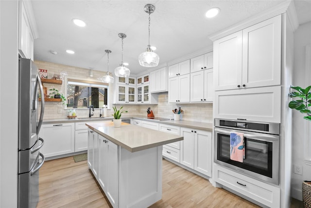 kitchen featuring light countertops, appliances with stainless steel finishes, light wood-type flooring, and a sink