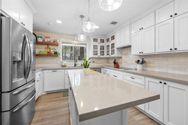 kitchen featuring stainless steel appliances, white cabinets, light countertops, and a kitchen island