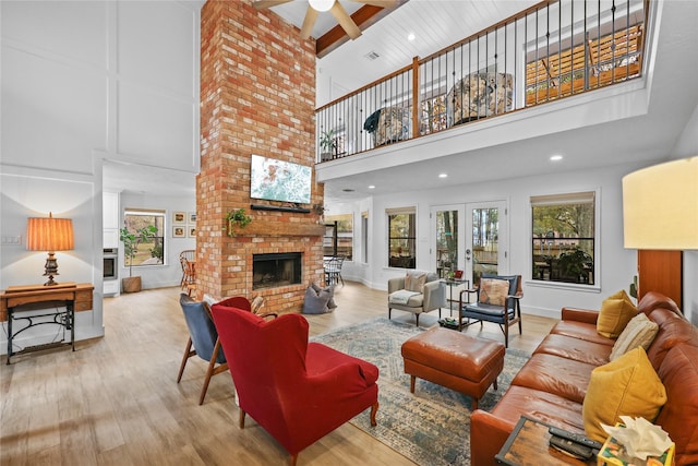 living room featuring a brick fireplace, a high ceiling, and wood finished floors