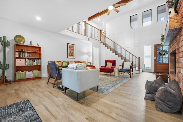 living room featuring stairway, beamed ceiling, wood finished floors, and a towering ceiling