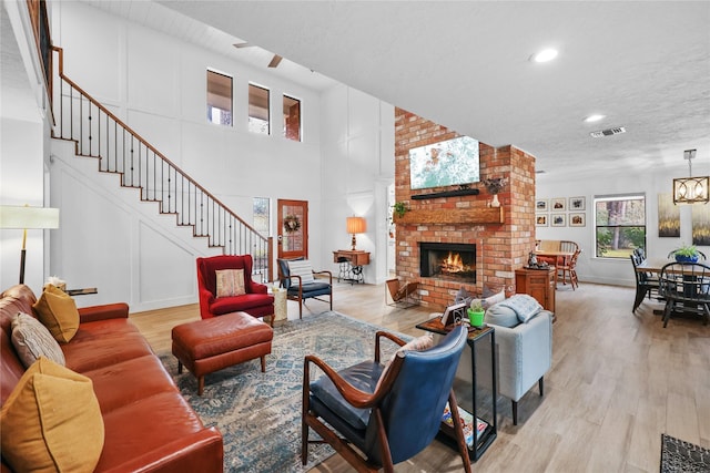 living area featuring light wood-type flooring, stairway, a fireplace, and visible vents