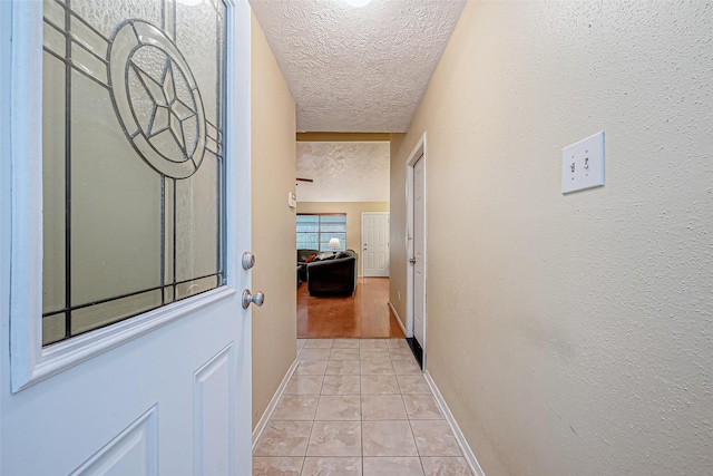 hallway with light tile patterned floors and a textured ceiling