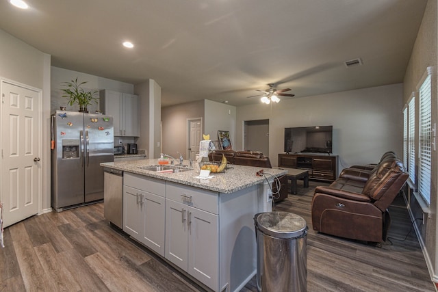 kitchen featuring sink, stainless steel appliances, light stone countertops, an island with sink, and white cabinets