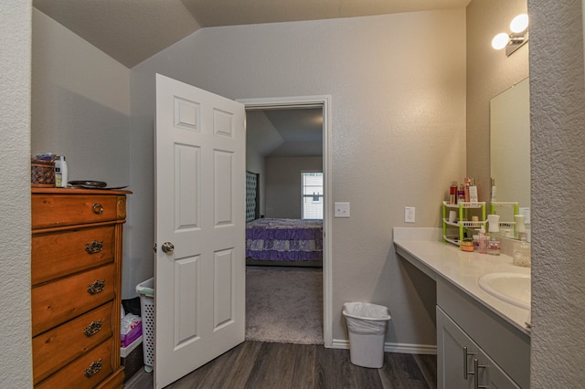 bathroom with hardwood / wood-style flooring, vanity, and vaulted ceiling