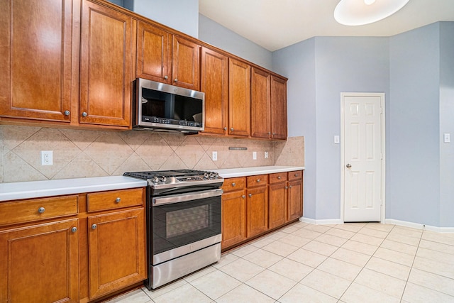 kitchen with light tile patterned flooring, appliances with stainless steel finishes, and backsplash
