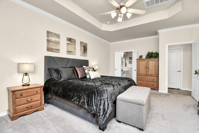 carpeted bedroom with a raised ceiling, ornamental molding, ensuite bathroom, and ceiling fan