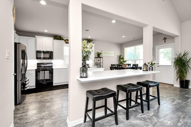 kitchen with white cabinetry, black appliances, a kitchen breakfast bar, and kitchen peninsula