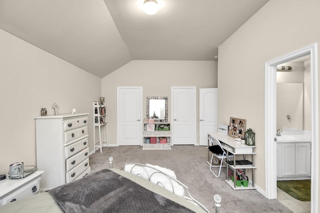 carpeted bedroom featuring ensuite bath and vaulted ceiling