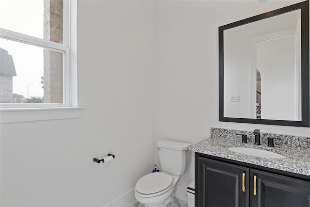bathroom with baseboards, toilet, and vanity