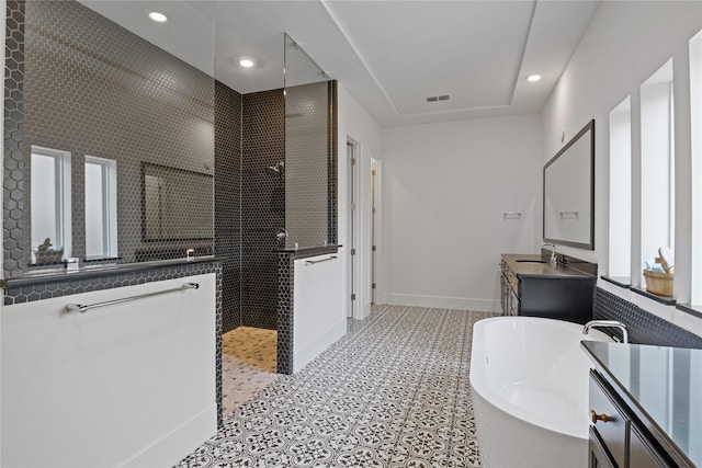 full bathroom featuring vanity, a freestanding tub, baseboards, recessed lighting, and a walk in shower