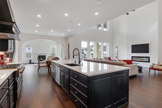 kitchen with a sink, dark cabinets, a glass covered fireplace, recessed lighting, and open floor plan