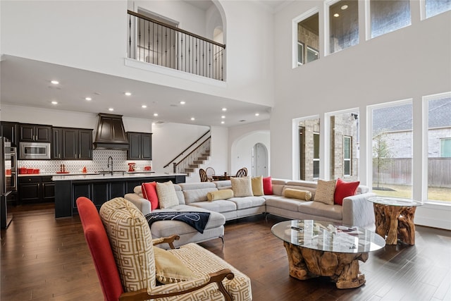living room featuring a high ceiling, dark wood finished floors, ornamental molding, and a wealth of natural light