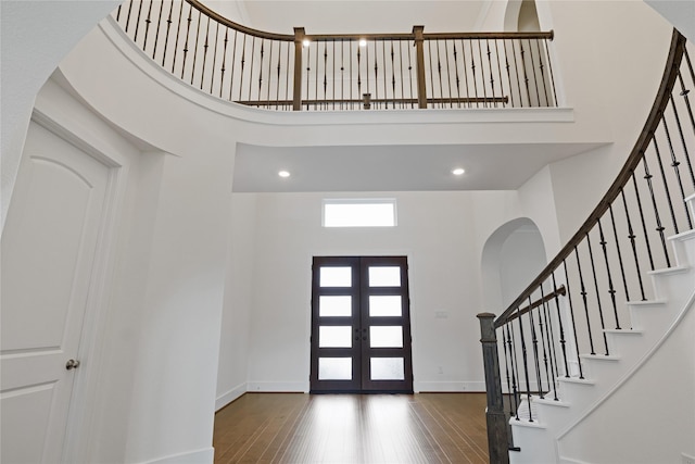 entryway featuring stairs, a high ceiling, baseboards, and hardwood / wood-style flooring