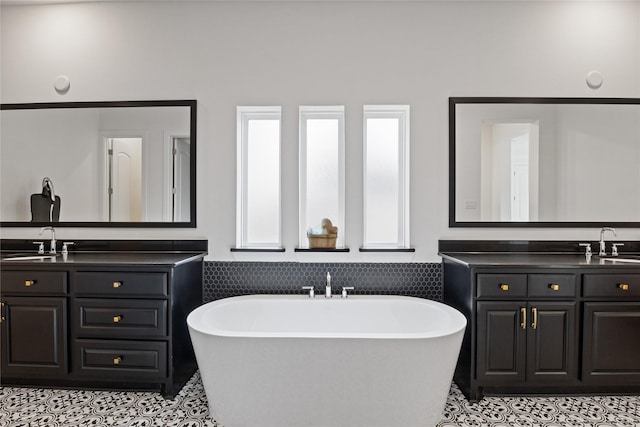 bathroom featuring a sink, a freestanding bath, and two vanities