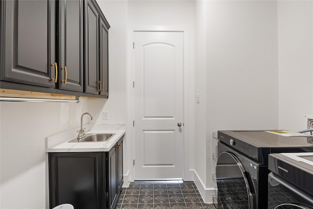 washroom with washing machine and dryer, baseboards, dark tile patterned floors, a sink, and cabinet space