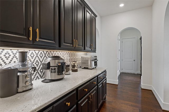 bar featuring light stone counters, backsplash, and dark hardwood / wood-style floors