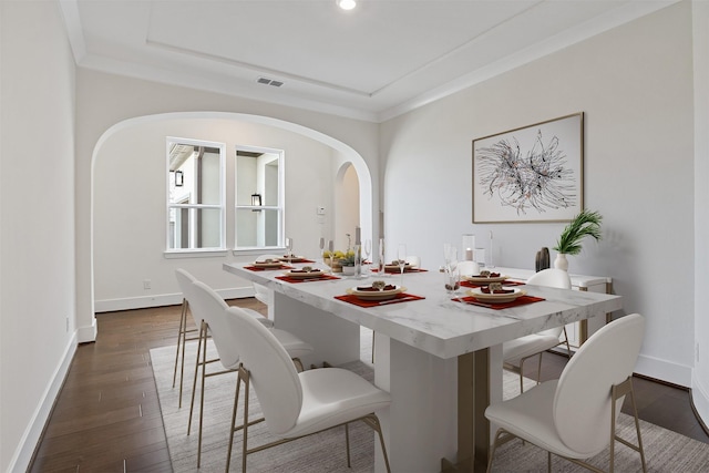 dining space with dark wood-style flooring, visible vents, arched walkways, baseboards, and ornamental molding