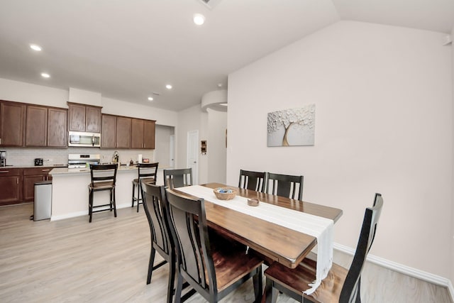 dining space featuring vaulted ceiling and light hardwood / wood-style floors