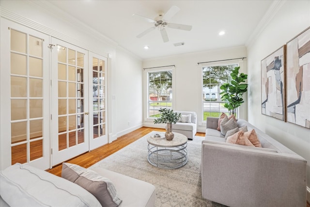 living room with ornamental molding, light wood-type flooring, and french doors