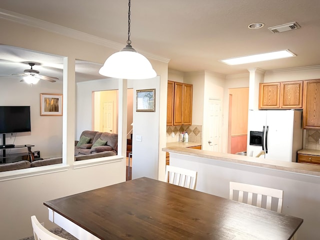 unfurnished dining area featuring ceiling fan, visible vents, and crown molding