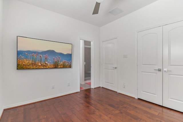 unfurnished bedroom featuring ceiling fan, a closet, and dark wood-type flooring