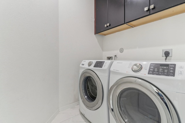 clothes washing area featuring washing machine and dryer and cabinets