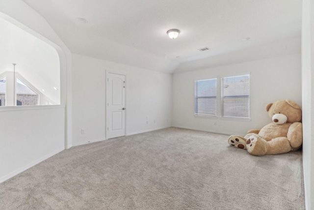 carpeted empty room with vaulted ceiling