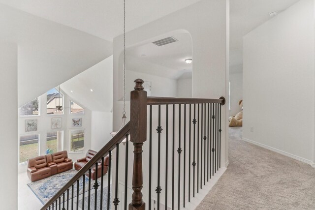 hall with high vaulted ceiling and light colored carpet