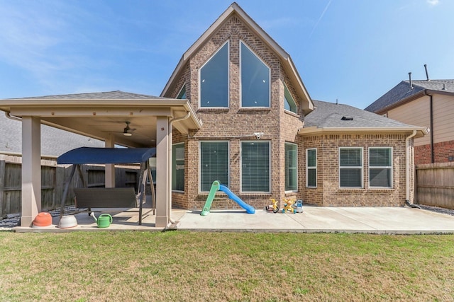 rear view of property with ceiling fan, a patio, and a yard