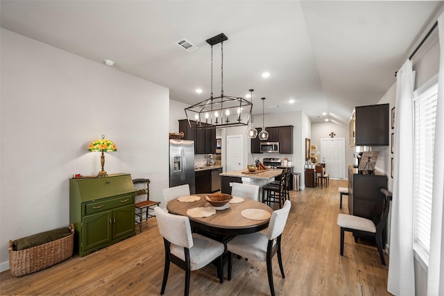 dining area featuring vaulted ceiling and light hardwood / wood-style floors