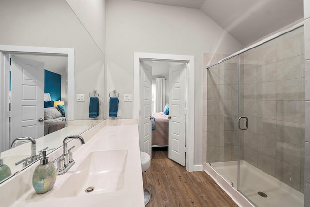 bathroom featuring sink, hardwood / wood-style floors, vaulted ceiling, a shower with shower door, and toilet