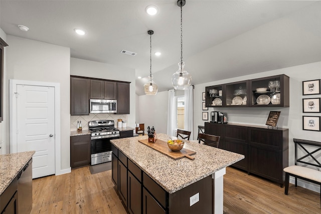 kitchen featuring dark brown cabinetry, stainless steel appliances, a center island, and light wood-type flooring