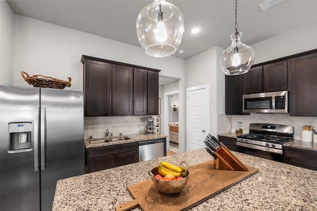 kitchen featuring dark brown cabinetry, sink, stainless steel appliances, and light stone countertops