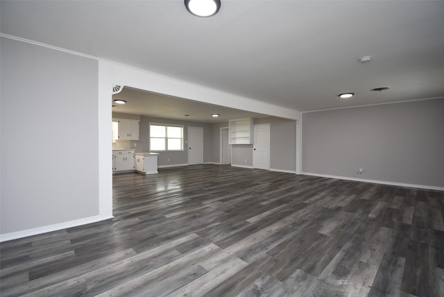 unfurnished living room featuring crown molding and dark wood-type flooring