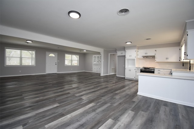 kitchen with sink, stainless steel range with electric stovetop, dark hardwood / wood-style flooring, decorative backsplash, and white cabinets