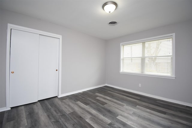 unfurnished bedroom featuring a closet and dark hardwood / wood-style floors