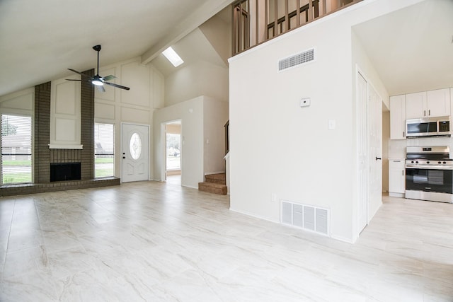 unfurnished living room featuring beam ceiling, a fireplace, high vaulted ceiling, and ceiling fan