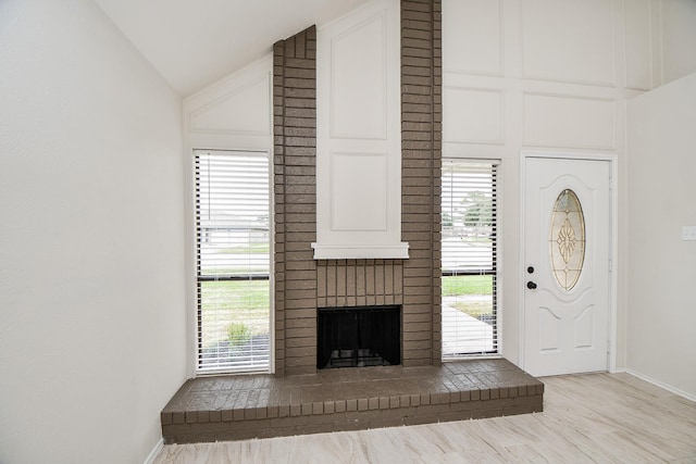 unfurnished living room featuring lofted ceiling, a fireplace, and light hardwood / wood-style flooring