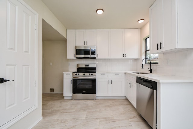 kitchen featuring stainless steel appliances, sink, white cabinets, and decorative backsplash