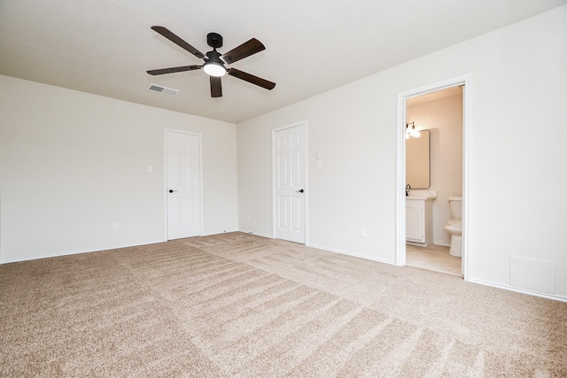 unfurnished bedroom featuring connected bathroom, light colored carpet, a closet, and ceiling fan