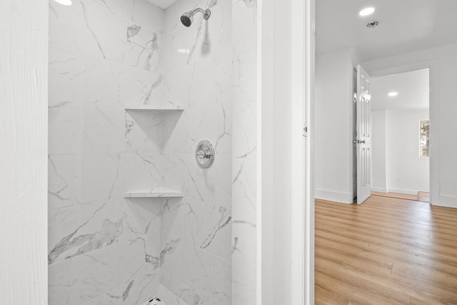 bathroom featuring hardwood / wood-style flooring and tiled shower