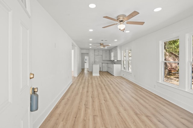 unfurnished living room with sink, light hardwood / wood-style floors, and ceiling fan