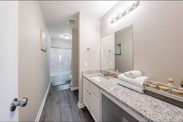 full bathroom with hardwood / wood-style flooring, vanity, shower / tub combination, and toilet