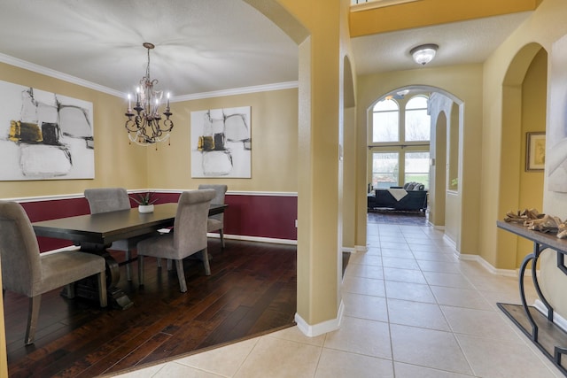 dining room with crown molding, light tile patterned floors, and an inviting chandelier