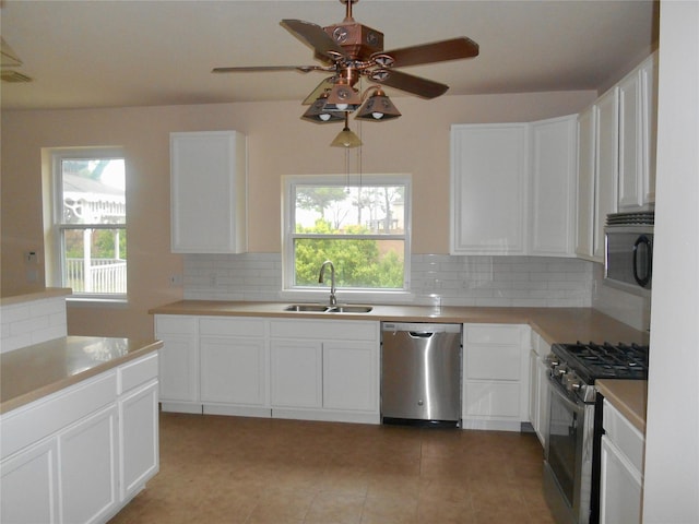 kitchen with stainless steel appliances, white cabinets, a wealth of natural light, backsplash, and sink