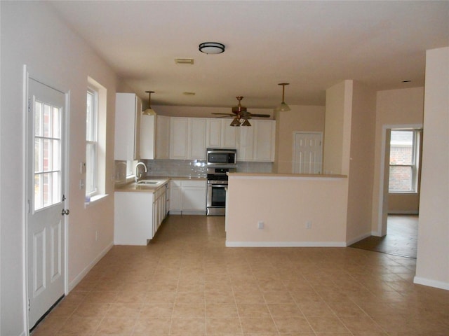 kitchen featuring appliances with stainless steel finishes, sink, white cabinetry, hanging light fixtures, and decorative backsplash