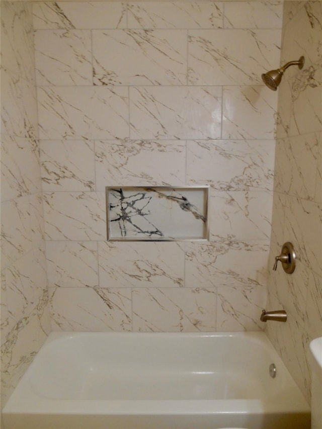 bathroom featuring toilet and tiled shower / bath